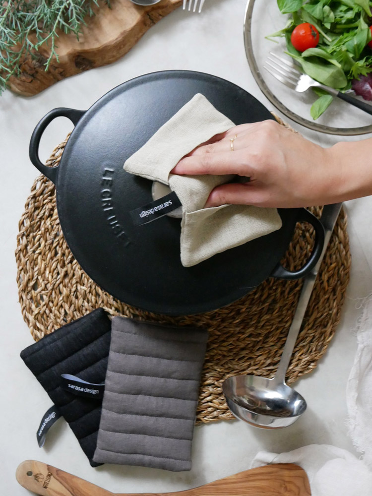 サラサデザインの麻リネンキッチングリルミトンとフライパン、ダッチオーブンなどの調理器具がキッチン台に並ぶ様子