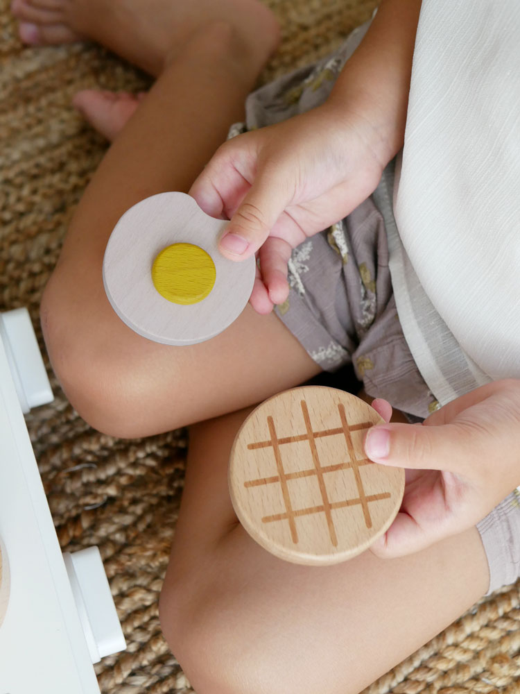 dou?ブランドのままごとがっき「pop pan」セット。ビーチ材とMDFで作られたフライパン、たまご、ハンバーグ、フライ返しが含まれ、10ヶ月以上のお子さま向けの安全なおもちゃ。