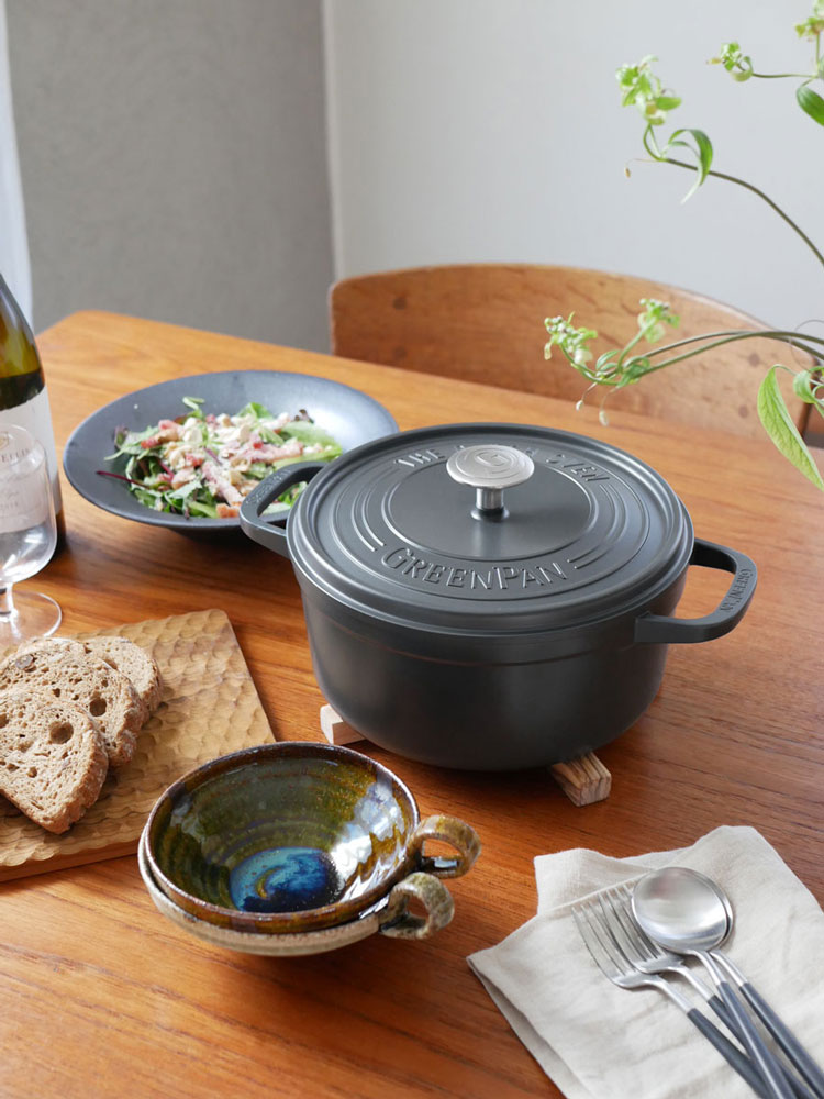 グリーンパンフェザーウェイトココットラウンドポットと蓋、シリコーン製ポットホルダー2個がテーブル上に並べられている