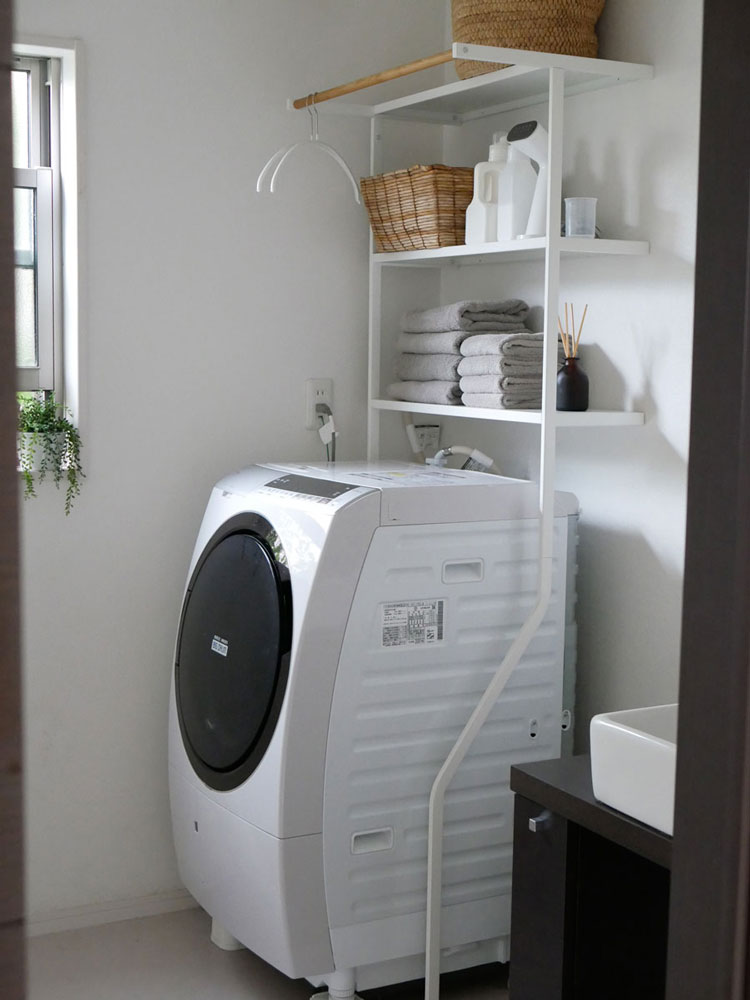 Yamazakiのタワーシリーズ、スチールと天然木で構成された高さ190cmの立て掛けランドリーシェルフ。幅75cm、奥行48cmの収納棚とハンガーバーを備えています。