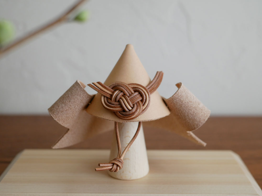 【Comore Sun】こどもと共に育つヌメ革の兜。ヌメ革で作られた伝統的なデザインの兜と、ブナ製のスタンドがセットになった商品画像。